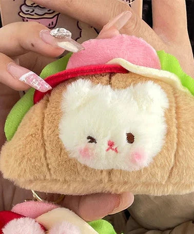 This little guy adds a dose of cute to your everyday carry with the Croissant Sandwich Bear Plush Keychain! This irresistibly cute accessory features a tiny, soft bear atop a buttery croissant sandwich, with all the fixin's. Perfect for fans of food-inspired designs, sandwich lovers, and all things bear-y-licious, this keychain brings all the kawaii charm.