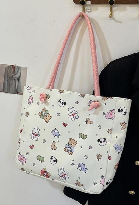 Fun, cute, and functional, this Everything Kawaii Print Shoulder Bag is a delightful bag featuring an enchanting all-over print. Showcasing adorable characters and designs: a playful panda, a cheerful bunny holding a carrot, a cuddly teddy bear, a narwhal with a magical horn, an all sorts of other whimsically happy delights!

This bag is perfect for school, work, or casual outings and is made from durable, nylon fabric with a soft pastel finish. It’s both stylish and practical with the double shoulder strap