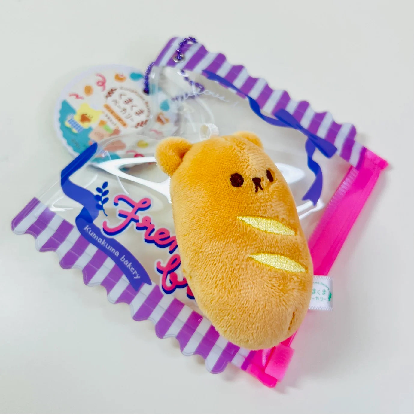 Say hello to the cutest little snack to carry your essentials! This unique Kuma Bakery Bear in a Bag Keychain French Baguette features a soft, squishy bear bread plushie tucked inside a charming purple-and-white striped mini wallet. The softness is like a mochi dessert and design is unmatched.