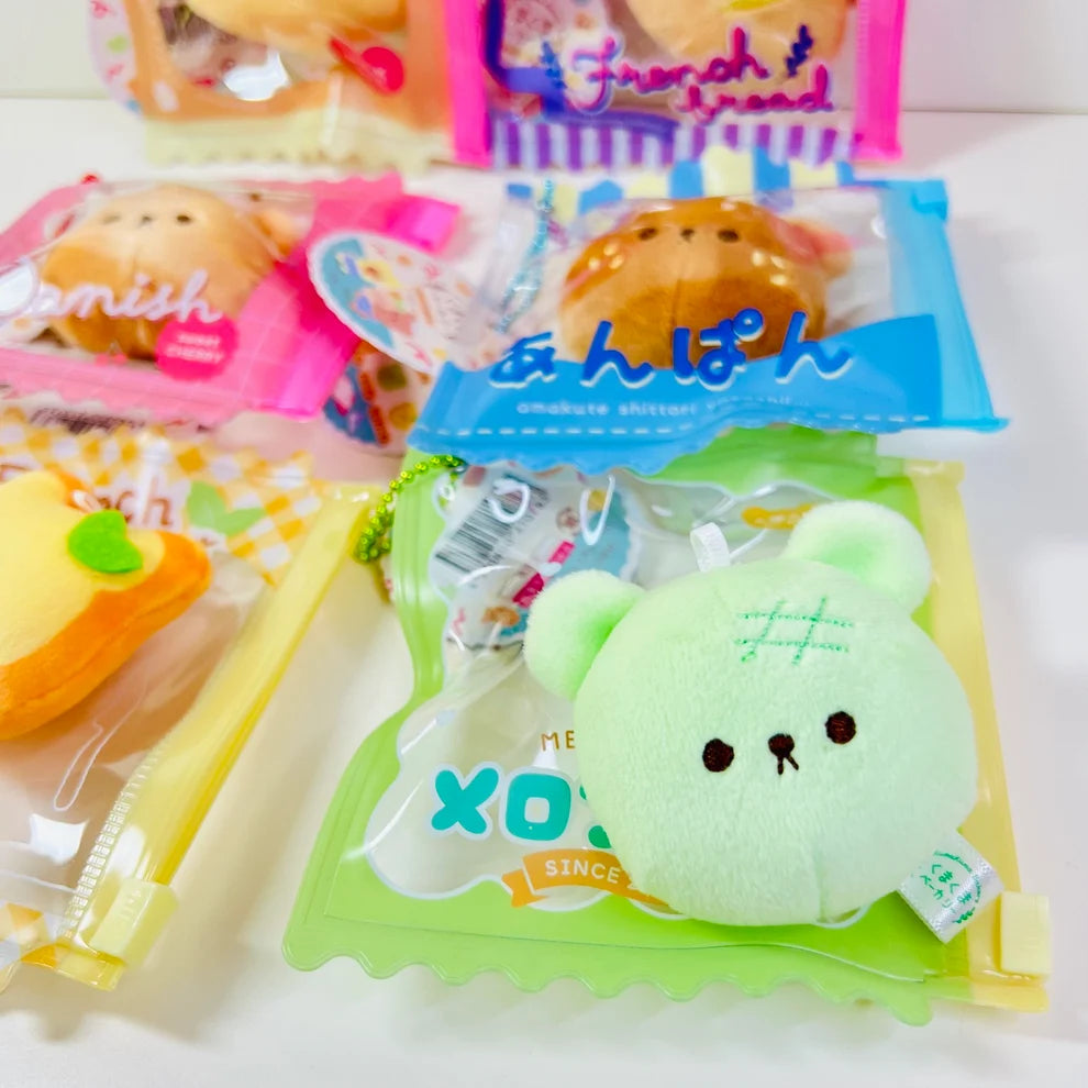 Say hello to the cutest little snack to carry your essentials! This unique Kuma Bakery Bear in a Bag Keychain, Melon Pan features a soft, squishy bear bread plushie tucked inside a charming clear and green mini wallet. The softness is like a mochi dessert and design is unmatched. Kawaii means cute in Japanese and this plushie keychain is as kawaii as you can get!