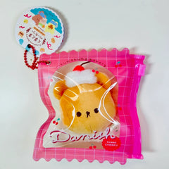Say hello to the cutest little snack to carry your essentials! This unique Kuma Bakery Bear in a Bag Keychain, Sweet Cherry Danish features a soft, squishy bread bear plushie tucked inside a charming clear and pink mini wallet. The softness is like a mochi dessert and the design is unmatched.