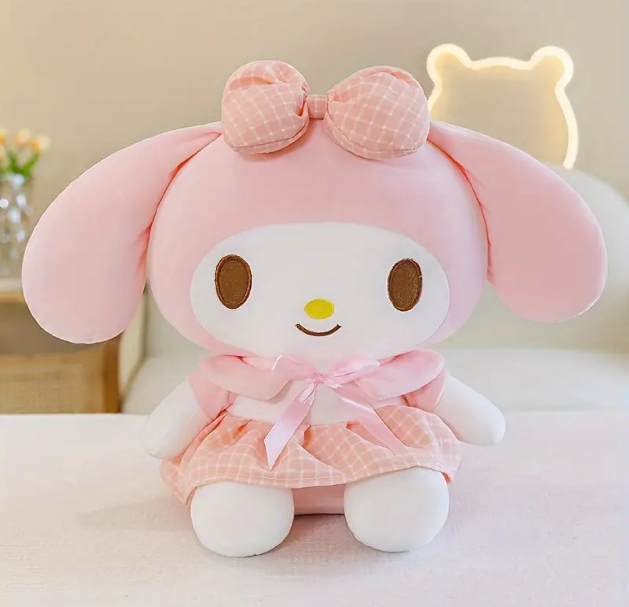 This My Melody "Pretty in Pink" Plaid Dress Plushie is a charming addition to any Sanrio collection! Dressed in a soft pink plaid dress with adorable details, My Melody is as sweet as ever, with her signature bunny ears and rosy cheeks. Made from ultra-soft, high-quality plush fabric, she's perfect for snuggling or adding a dash of cuteness to your room decor.

This plushie captures My Melody's gentle spirit and fashionable flair, making it an ideal gift for fans and collectors who love all things pastel an