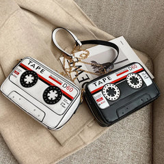 Take your style back in time with but with a fresh kawaii take with our Retro Cassette Tape Kawaii Street Style Black Shoulder Bag. This classy but funky, nostalgic accessory brings the charm of the '80s and '90s into modern-day fashion, combining a fun cassette tape design with streetwear vibes. It's styled to look like a classic cassette tape, complete with vibrant colors, fun graphics, and playful text, making it a perfect tribute to vintage music culture.