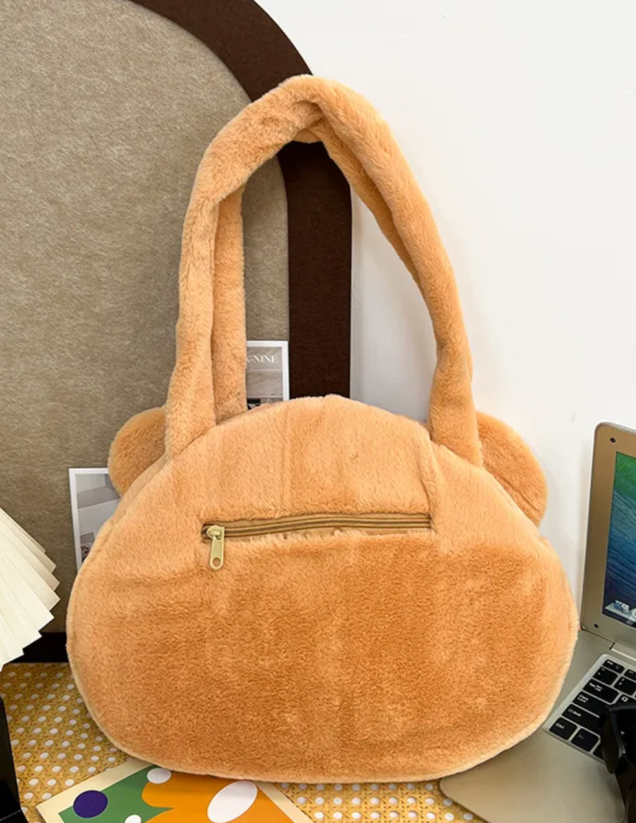 This Round Brown Bear Face Shoulder Bag brings the cute and functional Kawaii fashion. It features a charming brown bear head with embroidered face details and an adorable leaf upon its head, adding an even more playful touch to your look.  Made from soft, durable plush fabric that feels great to the touch, and a secure zipper closure to keep your belongings safe and easily accessible. Its interior is nice and spacious for all of your needs.