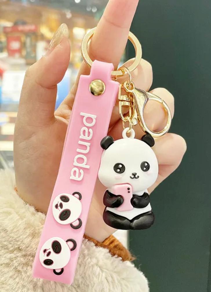 These happy pandas are having an extroverted day! Choose from the neighborly waving panda with a little heart on its chest, or the joy-scrolling panda about to take its best selfie of the day. The Social Panda Friend Keychain includes a gold metal keyring and durable pink rubber strap to keep your panda friend (and your keys) secure.