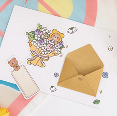 This Spring Bouquet Bear Greeting Card &amp; Bookmark will make greeting loved ones even sweeter! Upon opening the card, the recipient will discover a dainty yet elegant removable bouquet piece and a charming bookmark.