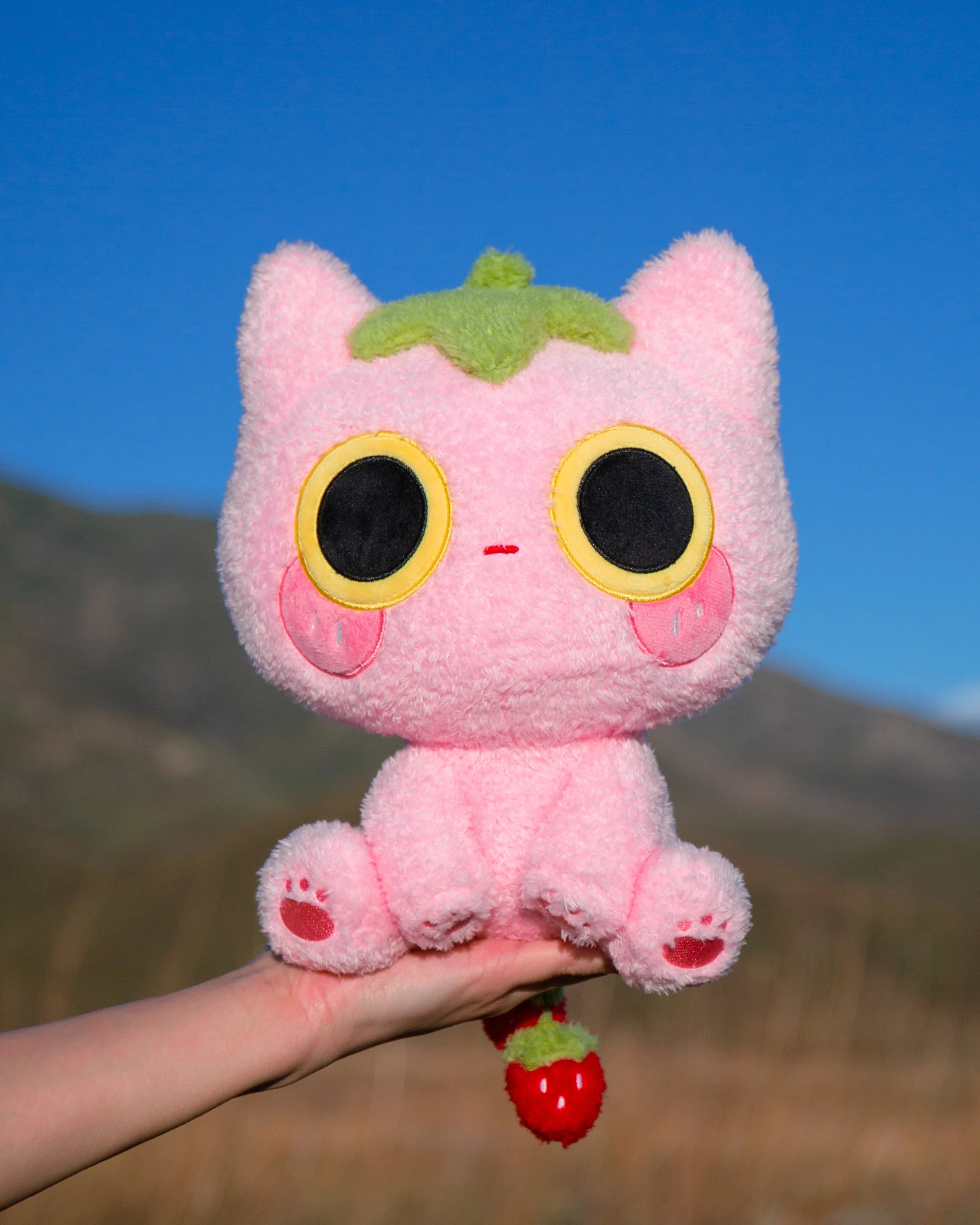 Soft, silly, and full of love, Strawmi is boutique designer MikouArt's sweetest design! Strawmi’s iconic strawberry head and tail are made with custom materials and sewing techniques. Two tiny, movable strawberries on the tail add some extra playful charm. Strawberries are the essential kawaii fruit for good reason- Strawmi makes the perfect unique gift for fans and collectors of all things strawberry-themed!